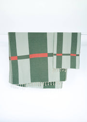 Green and red checkered Turkish towel with tassels on a white background