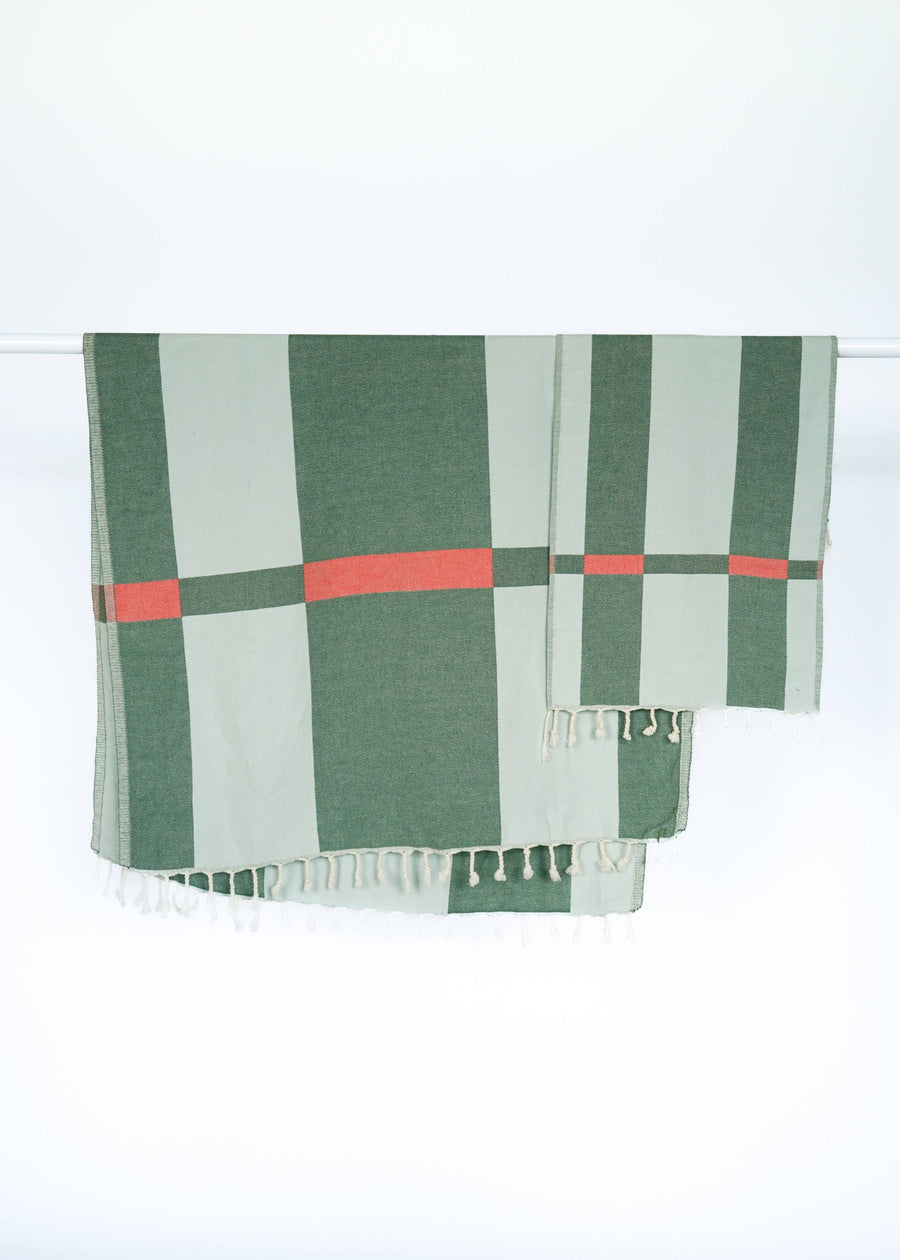 Green and red checkered Turkish towel with tassels on a white background