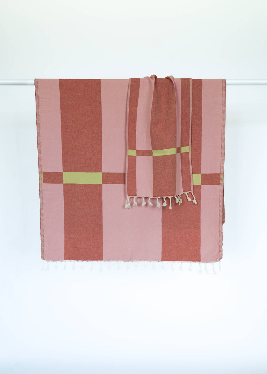 Striped Turkish towel with pink and red geometric pattern on a white background